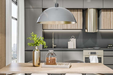 Front view on stylish eco interior kitchen room with glossy gray kitchen set, modern lamp above wooden table, round kitchen hood and green tree branches in golden shadows metallic vase. 3D renderingの写真素材