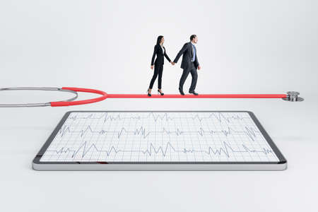Young european businessman and woman walking on stethoscope above tablet with cardiology screen on...