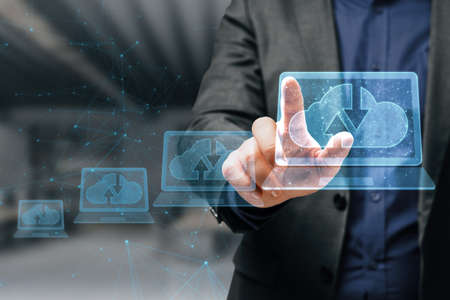 Close up of businessman hand pointing at abstract polygonal digital laptop with cloud computing hologram on blurry interior background. database and information concept. double exposureの写真素材