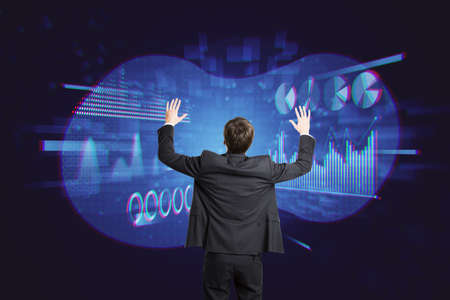 Back view of attractive young european businessman using abstract glowing digital business chart and...