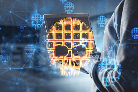 Close up of hacker hands using laptop with skull hologram on blurry office interior background....