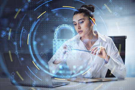 Attractive young european businesswoman sitting and using laptop with glowing security padlock on...