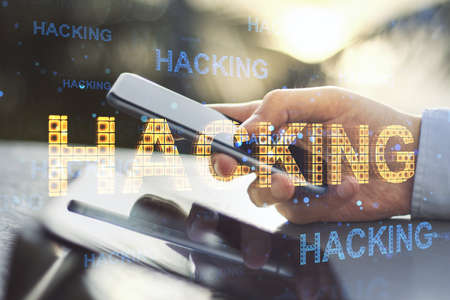 Close up of businessman hands using tablet and smartphone with abstract glowing hacking hologram at...