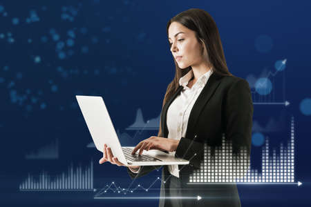 Attractive young caucasian businesswoman using laptop with abstract glowing business chart hologram...