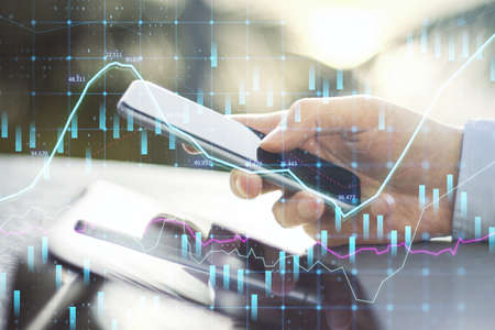 Close up of hands using tablet and smartphone at desktop with abstract glowing forex graph on blurry...