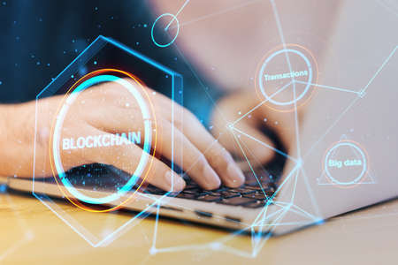 Close up of hands using laptop keyboard with creative polygonal blockchain hologram on blurry background. Technology, crypto, financial data and fintech concept. double exposureの写真素材
