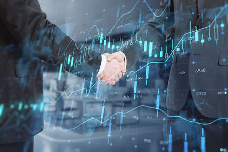 Close up of businessmen shaking hands with creative glowing forex chart hologram with map on blurry...