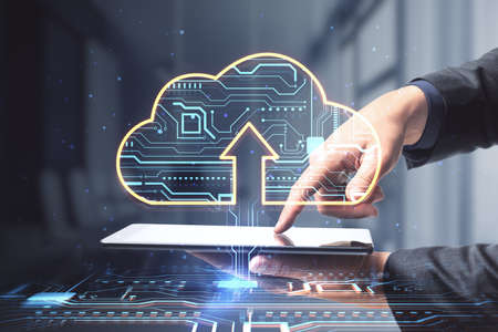 Close up of businessman hands pointing at tablet with glowing circuit cloud hologram on blurry...