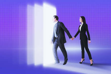 Young businessman and businesswoman walking into metaverse world on glowing background. Meta, technology and innovation conceptの写真素材