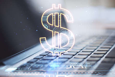 Close up of laptop with creative glowing dollar sign hologram on blurry background. Online banking, technology and currency conceptの写真素材