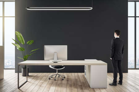 Businessman standing in modern office interior with furniture and other objects. CEO and executive conceptの写真素材