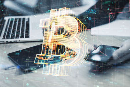 Close up of businessman hands using tablet and smartphone on desktop with creative glowing bitcoin hologram on blurry background. Cryptocurrency and finance concept. double exposureの写真素材