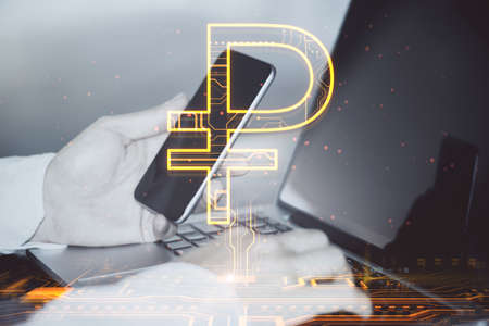 Close up of male hands using laptop and smartphone on desktop with creative glowing Russian ruble hologram on blurry background. Digital money and online banking concept. double exposureの写真素材