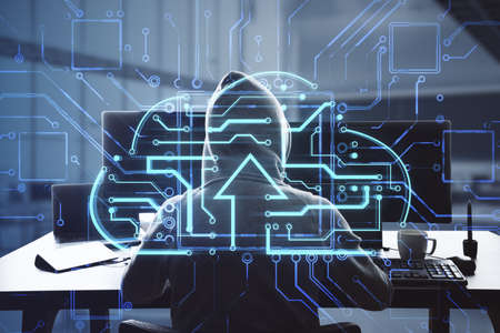 Back view of hacker at desktop using laptop computer monitors with abstract glowing circuit cloud hologram on blurry office interior background. Big data, data theft and technology concept. double exposureの写真素材