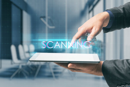 Close up of businessperson hand pointing at tablet with creative digital text hologram on blurry office interior background. Information, scanning, technology and big data concept.の写真素材