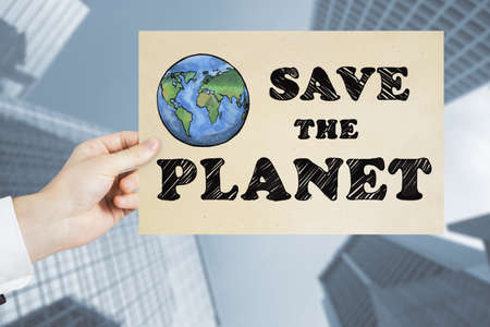 Close up of man hand holding save the planet sketch on blurry city background. earth day conceptの写真素材