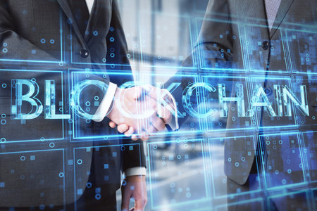 Close up of businessmen shaking hands with creative blue cubes blockchain text hologram. Technology...