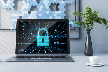 Close up of office workplace with laptop and abstract glowing padlock hologram with coffee cup on...