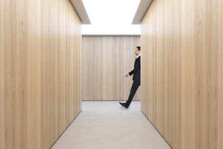 Businessman walking in modern hardwood hallway interior with mock up place on wall. Design and texture conceptsの写真素材