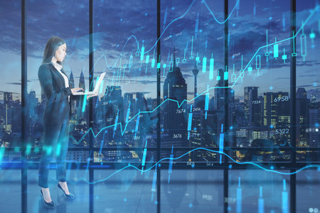 Attractive young european businesswoman with laptop computer looking at glowing candlestick forex...