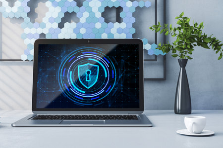 Close up of laptop on desktop with creative glowing blue padlock hologram, coffee cup, decorative...