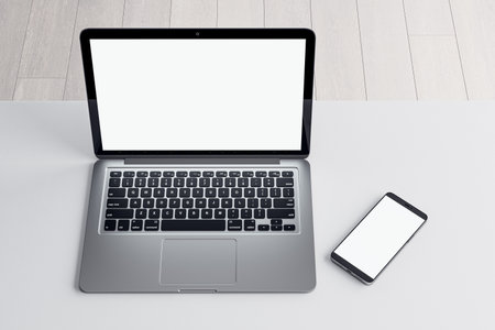Close up of empty white laptop and cellphone on light desktop, mock up place on screen, wooden parquet flooring background. top view. 3D Renderingの写真素材