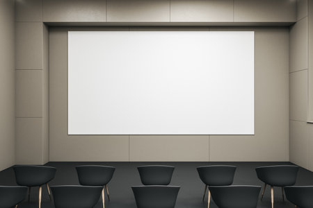 Front view on blank white wall board with space for your logo or text on light beige wall in empty auditorium with black seats. 3D rendering, mockupの写真素材