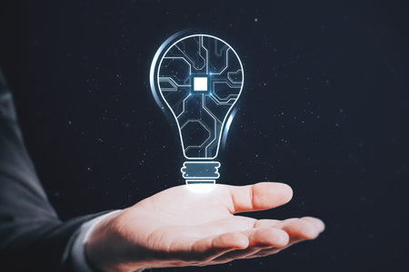 Close up of businessman hand holding abstract glowing light bulb with chip hologram on blurry dark background. artificial intelligence and neural network conceptの写真素材