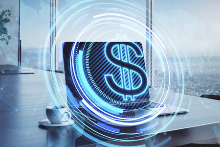 Close up of laptop on desktop with coffee cup and creative glowing round dollar icon and map hologram on blurry office background. Finance, currency and global business technologies concept. double exposureの写真素材