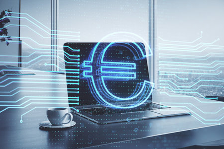 Close up of laptop and coffee cup on desktop with glowing euro hologram on blurry office interior background with window and city view. Money, banking app and finance concept. double exposureの写真素材