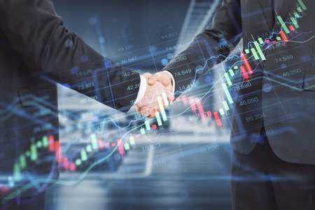 Close up of businessmen shaking hands in office with creative candlestick forex chart index hologram...