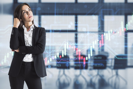 Attractive thoughtful young european businesswoman with creative candlestick forex chart index hologram on blurry office interior background. Trade, business market and finance analysis concept. double exposureの写真素材
