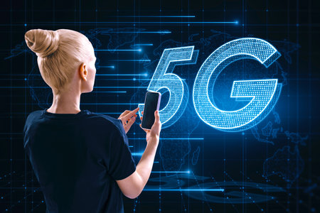 Attractive blonde woman using cellphone with glowing 5G hologram on blurry background. Wireless...