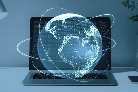 Close up of laptop computer on desktop with creative glowing globe hologram on blurry background....