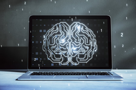 Close up of laptop on desktop with glowing human brain hologram on screen and blurry background....