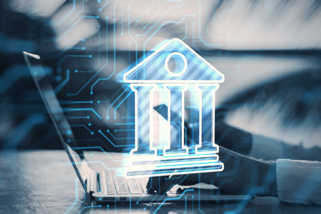 Online banking concept. Close up of males hands holding smartphone and using laptop with bank app hologram on blurry outdoor background. double exposureの写真素材