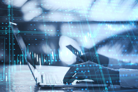 Close up of male hands using laptop and cellphone with glowing candlestick forex grid chart on...