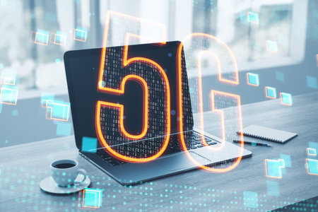 Close up of laptop on desktop with coffee cup and glowing 5g hologram on blurry background. 5G...