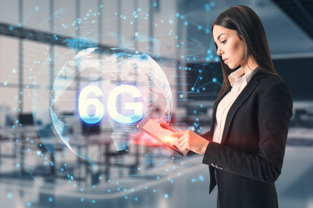 Young businesswoman using tablet with globe and 6g hologram on blurry office interior background....