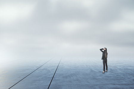 Businesswoman looking into the distance on abstract gloomy sky and ground background with mock up placeの写真素材