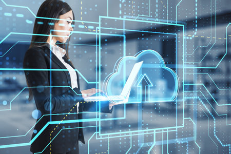 Young european businesswoman using laptop with glowing circuit cloud computing hologram on blurry...