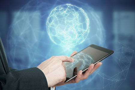 Close up of man hand pointing at mobile phone with glowing polygonal globe hud on blurry background. Futuristic technology wireframe mesh polygonal element. Social Network Graphic Conceptの写真素材