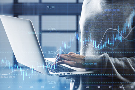 Close up of hacker hand using laptop with glowing candlestick forex chart with index on blurry...
