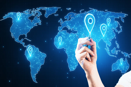 Close up of hand with pen pointing at glowing map with location pins on blurry blue background. GPS...