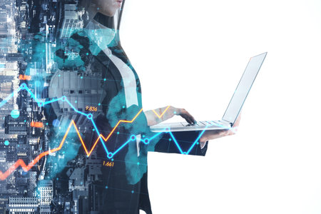 Woman using laptop with glowing upward forex chart on blurry city background. Trade, finance, success and stock concept. double exposureの写真素材