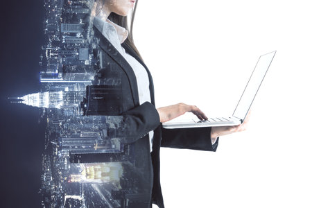 Headless young businesswoman using laptop on abstract sideways city background. Success, work, job and career concept. double exposureの写真素材