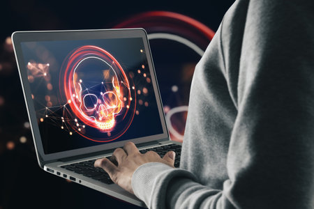 Hacker using laptop with digital red skull hologram on dark background. ransomeware, virus and pirate threat concept. double exposureの写真素材