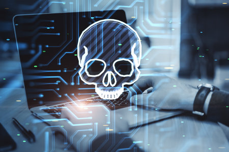 Close up of hands using laptop with glowing skull hologram on blurry background. Hacker system or cyber attack concept. double exposureの写真素材