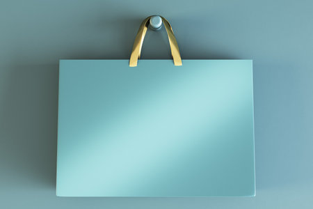 Shopping or present concept with front view on blank blue craft bag with golden handles and place for company logo or advertising text on light turquoise wall background. 3D rendering, mockupの写真素材