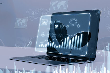 Close up of laptop at office workplace with business chart hologram on blurry background. Financial...